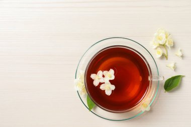 Sıcak yasemin çayı fincanda ve çiçekler beyaz ahşap masada, düz yerde. Metin için boşluk