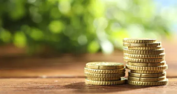 stock image Stacked euro coins on wooden table, space for text