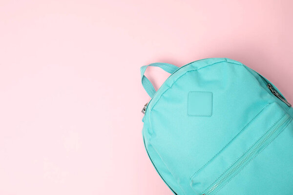 Один бирюзовый рюкзак на розовом фоне, вид сверху. Пространство для текста
