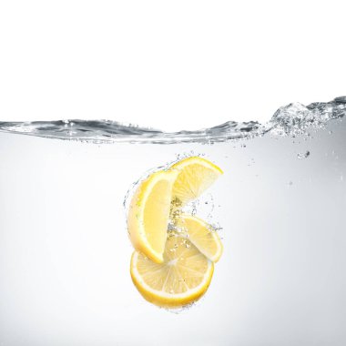 Beyaz arkaplanda suya düşen taze limonlar
