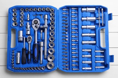 Oto tamircisinin aletleri beyaz ahşap masa üzerindeki plastik kutuda, üst görünümde.