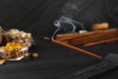 Bulanık arkaplanda yanan tütsü çubuğu, yakın plan.
