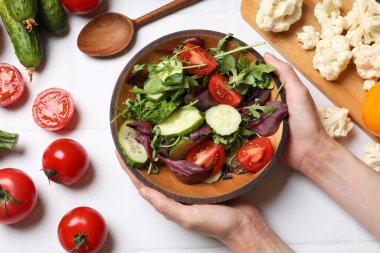 Sağlıklı vejetaryen yemekleri. Sebzeli, beyaz fayanslı tabakta salata tutan kadın.