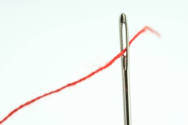 Beyaz arkaplanda kırmızı iplikli dikiş iğnesi, yakın plan