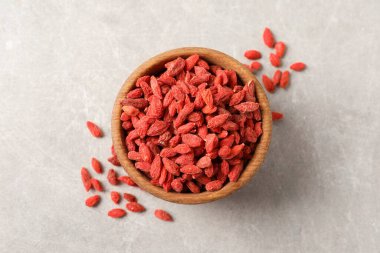Açık gri masada kasede kurumuş goji üzümleri, üst manzara.