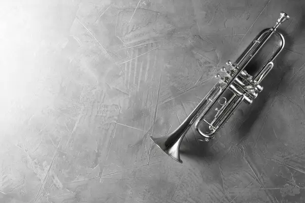 stock image Shiny trumpet on grey textured table, top view. Space for text. Wind musical instrument