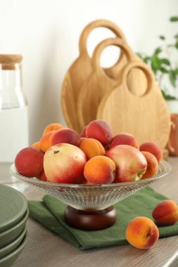 Mutfaktaki ahşap tezgahta farklı taze meyveler bulunan cam vazo.