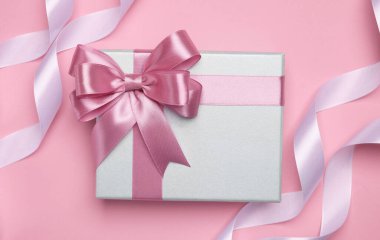 Pembe arka planda renk yaylı ve kurdeleli güzel hediye kutusu, düz yatıyordu.