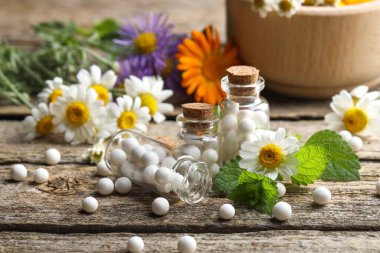 Homeopatik tedavi. Bir sürü hap, şişe ve papatya çiçekleri ahşap masada, yakın plan.