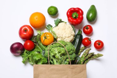 Vejetaryen ürünlerin teslimatı. Farklı sebzelerle dolu çantalar ve beyaz arka planda meyveler.