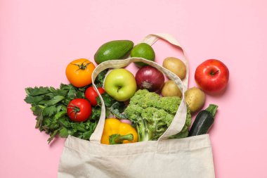 Vejetaryen ürünlerin teslimatı. Farklı sebzelerle dolu çantalar ve pembe arka planda meyveler.