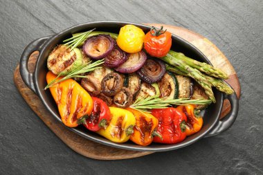 Gri desenli masada, fırında pişirme kabında nefis ızgara sebzeler.