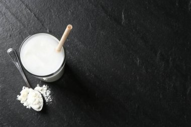 Bardakta leziz protein karışımı ve siyah masa üzerinde toz bulunan kaşık, üst manzara. Metin için boşluk