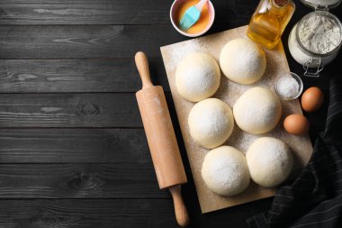 Çiğ hamur topları, yumurta sarısı, un, yumurta ve yuvarlak raptiye siyah ahşap masa, üst manzara. Metin için boşluk