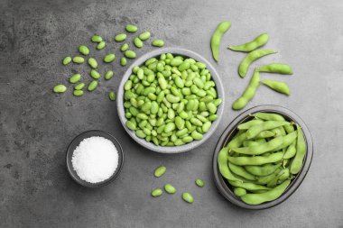 Çiğ yeşil edamame soya fasulyesi ve kapsülleri gri masada, düz yerde.