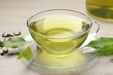 Yeşil çayı fincanda tazeleyen ve ahşap masada yapraklar, yakın plan