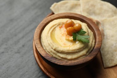 Zeytinyağlı lezzetli humus, kasede nohut ve gri masada pide, yakın plan.