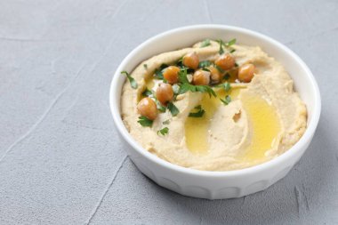 Zeytinyağı, nohut ve maydanozlu lezzetli humus gri desenli masada.