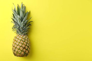 Sarı arka planda taze, olgun bir ananas. Metin için boşluk
