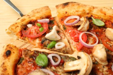 Tahta masada fesleğenli, mantarlı, soğanlı ve domatesli lezzetli pizza.