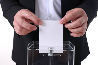 Beyaz arka plana karşı oy sandığına oy veren adam, yakın plan.