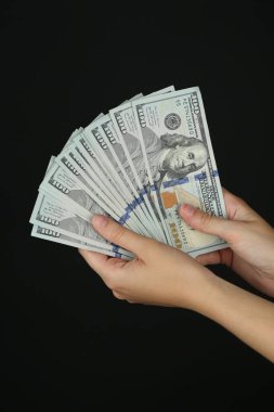 Siyah arka planda dolar banknotları olan kadın, yakın plan.