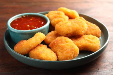 Acı biber soslu tabak ve ahşap masada nugget, yakın plan.