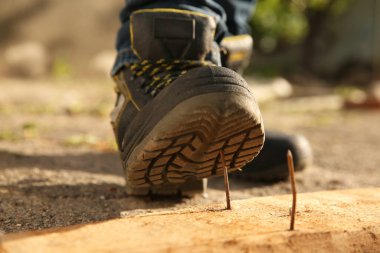 Dikkatsiz işçiler tahta çiviye basıyor, yakın plan.