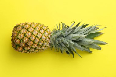 Sarı arka planda taze, olgun bir ananas.