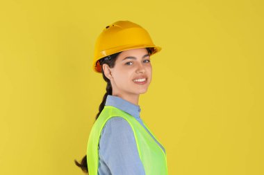 Sarı arka planda sabit şapkalı mühendis.
