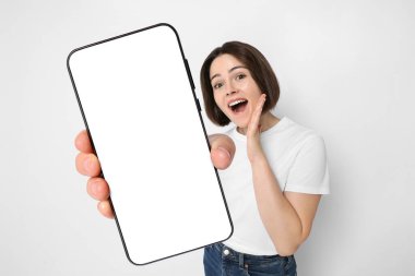 Beyaz arka planda boş ekranlı cep telefonu gösteren mutlu bir kadın. Tasarım için model