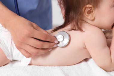 Pediyatrist, klinikte steteskoplu şirin bir kızı muayene ediyor. Bebeğin sağlığını kontrol ediyorum.