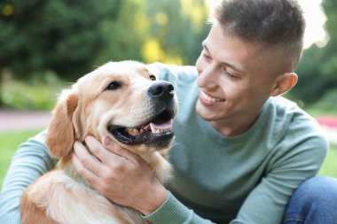 Parkta sevimli köpeğiyle genç bir adam.
