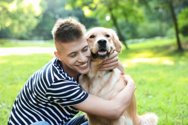 Parkta sevimli köpeğiyle genç bir adam.