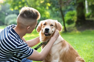 Parkta sevimli köpeğiyle genç bir adam.