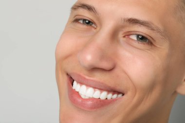 Gri arka plandaki mutlu genç adam, yakın plan. Diş kaplamaları