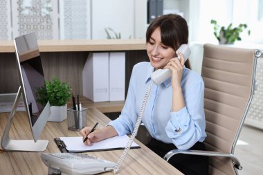 Ofiste telefonla konuşan profesyonel resepsiyonist.