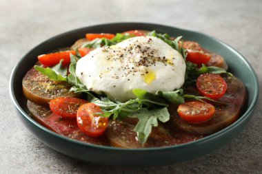 Gri desenli masada kasede taze burrata salatası, yakın plan.