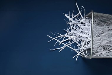 Mavi ahşap masadaki çöp kutusunda kağıt şeritler, üst manzara. Metin için boşluk