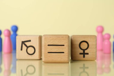 Cinsiyet eşitliği kavramı. Açık sarı arka planda dişi ve erkek sembolleri olan tahta küpleri.