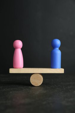 Cinsiyet eşitliği kavramı. Erkek ve kadın figürleri gri arkaplanla karşılaştırılıyor