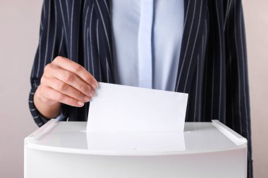 Kadın oyunu gri arka planda sandığa koyuyor, yakın plan.