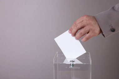 Adam oyunu gri arkaplana karşı sandığa koyuyor, yakın plan. Metin için boşluk