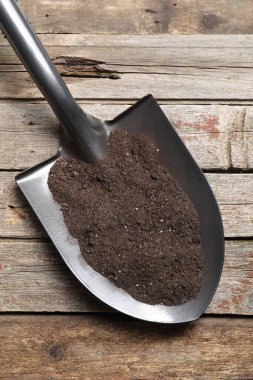 Tahta masanın üzerinde toprak olan metal kürek, üst manzara.