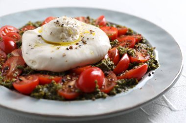 Taze lezzetli burrata salatası beyaz masada, yakın plan.