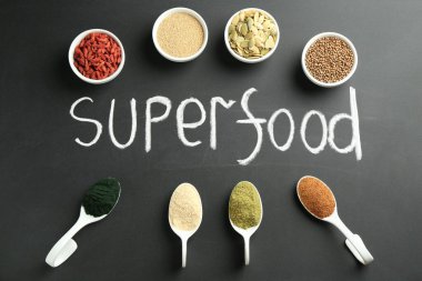 Superfood kelimesi ve siyah masa üzerindeki farklı sağlıklı tozlar.