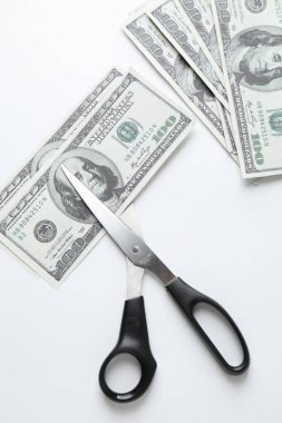 Bütçe belirleme. Beyaz arkaplanda dolar banknotları ve makas, üst görünüm