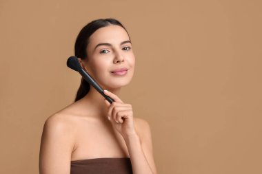 Güzel makyaj. Bej arka planda fırçası olan çekici kadın, metin için boşluk