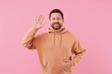 Pembe arka planda sallanan neşeli yakışıklı adam.