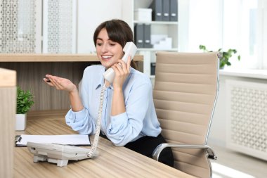 Ofiste telefonla konuşan profesyonel resepsiyonist.